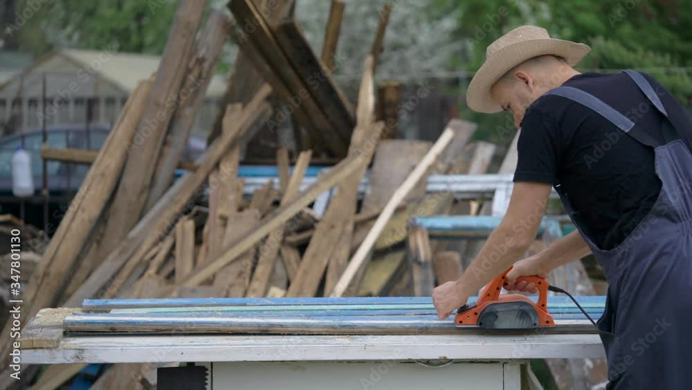The man works as an electric bank. Processing old boards. Dealing with wood. The man works as an electric bank. Processing old boards. Dealing with wood.