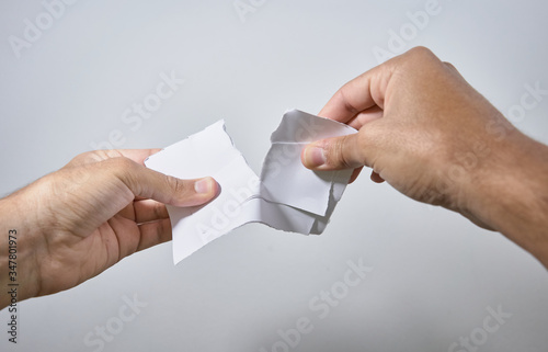 hands breaking a sheet of paper on white background