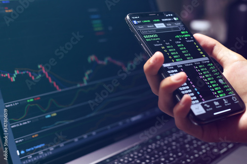The Stock Exchange, Streaming Trade Screen, The stock screen Show the stock price rise, Trader hold the phone in hand.