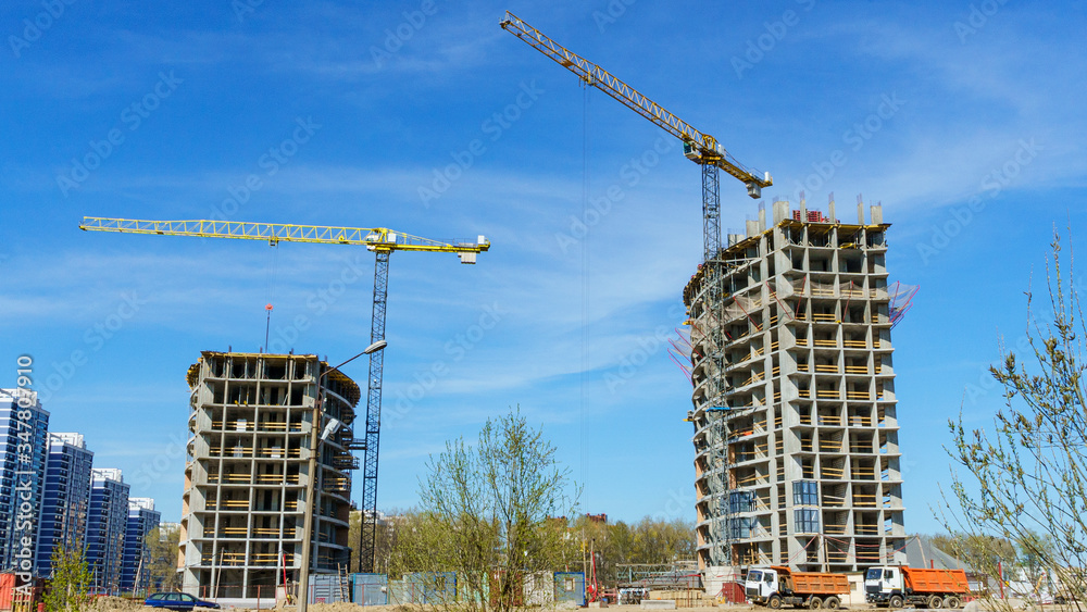 Fototapeta premium Construction site with two cranes against the classic blue sky.
