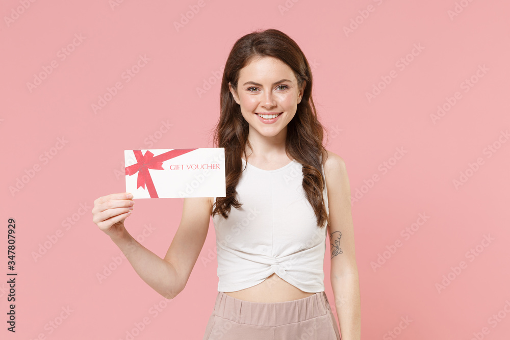 Smiling young brunette woman girl in light casual clothes posing isolated on pastel pink wall background studio portrait. People emotions lifestyle concept. Mock up copy space. Hold gift certificate. Smiling young brunette woman girl in light casual clothes posing isolated on pastel pink wall background studio portrait. People emotions lifestyle concept. Mock up copy space. Hold gift certificate.