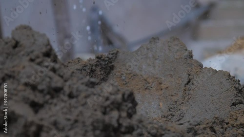 Wallpaper Mural person mixes wet cement with metal shovel on ground against blurry yellow pile slow motion close view. Concept slavery and poverty Torontodigital.ca