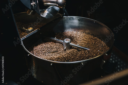 Shiny stainless large metal vat for roasting coffee beans close-up on dark background. The concept of industrial cooking arabica and robusta.