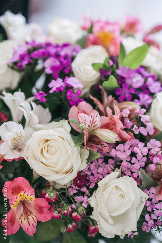 A bright, luxurious bouquet of colorful alstromeria and white roses. Photo with blurred background.