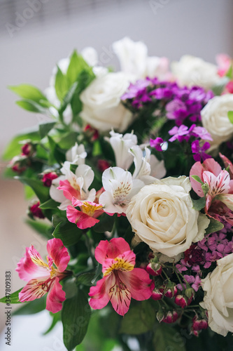 A bright, luxurious bouquet of colorful alstromeria and white roses. Photo with blurred background.