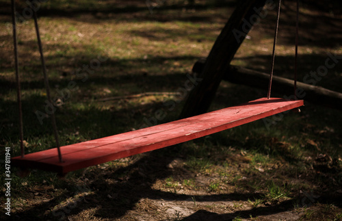 Huśtawka z dwóch desek pomalowana na czerwono w letnie popołudnie