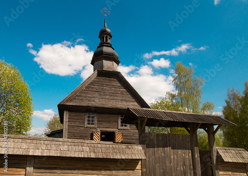 Pleasant sunny summer landscape: old blue sky and clouds, green trees and old historical Slavic Orthodox country church building . A happy idyllic scenery view