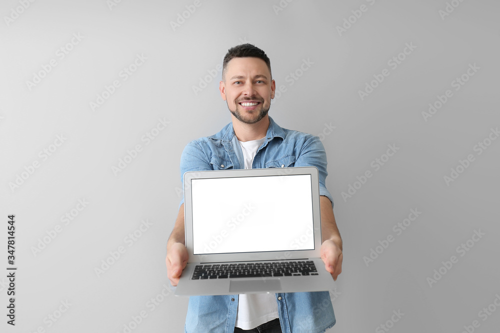 Handsome man with laptop on grey background Handsome man with laptop on grey background