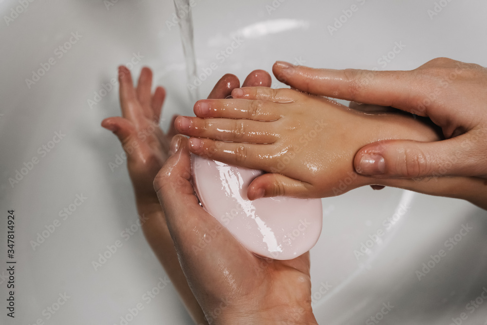 mom washes her baby's hands thoroughly with soap and foam in the bathroom for hygiene purposes, hands closeup mom washes her baby's hands thoroughly with soap and foam in the bathroom for hygiene purposes, hands closeup