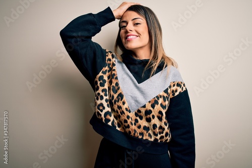 Young beautiful woman wearing casual sweatshirt standing over isolated white background smiling confident touching hair with hand up gesture, posing attractive and fashionable