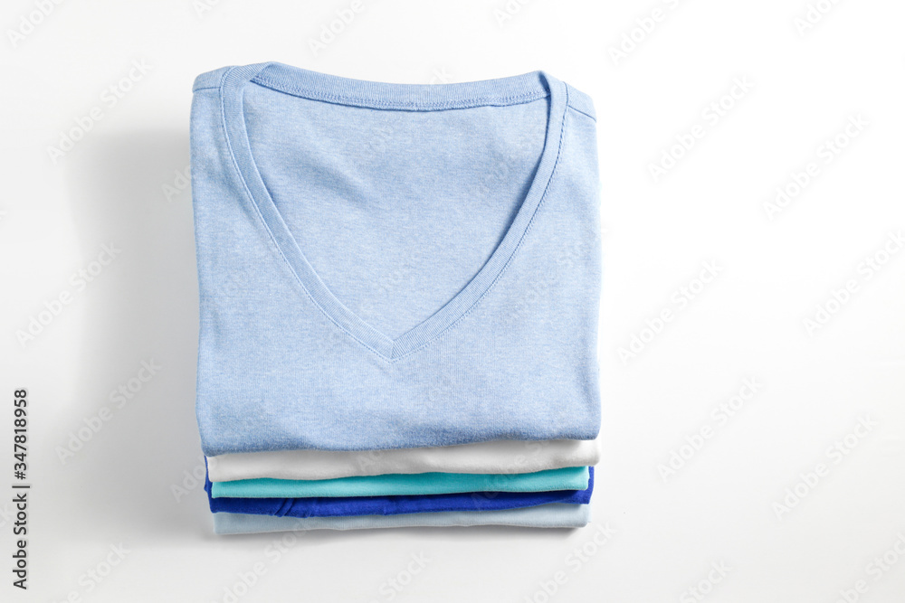 Stack of colorful perfectly folded clothing items. Pile of different pastel color shirts and sweaters isolated on white background. Close up, top view, copy space. Stack of colorful perfectly folded clothing items. Pile of different pastel color shirts and sweaters isolated on white background. Close up, top view, copy space.
