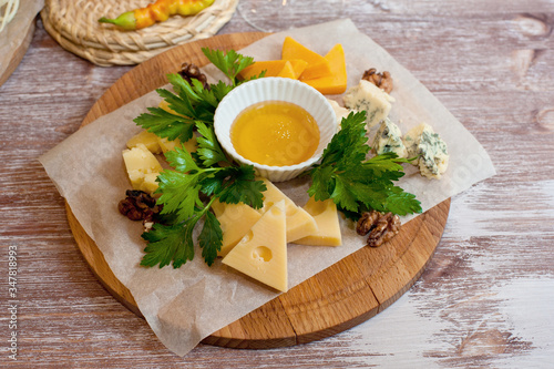 Still life cheese dish with nuts and honey on a wooden Board