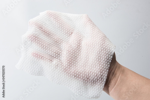 A paper towel is held in one hand for thickness testing against a white background.