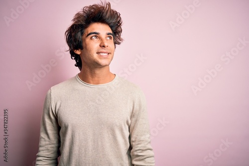 Young handsome man wearing casual t-shirt standing over isolated pink background smiling looking to the side and staring away thinking.