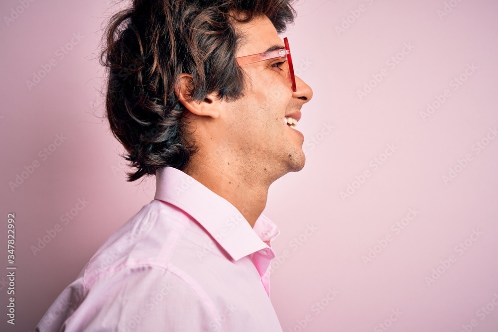 Young handsome man wearing glasses with heart form over isolated pink background looking to side, relax profile pose with natural face with confident smile. Young handsome man wearing glasses with heart form over isolated pink background looking to side, relax profile pose with natural face with confident smile.