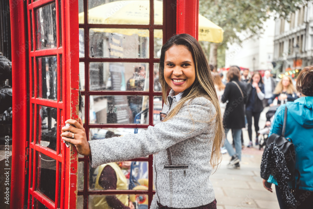 Pretty girl entering red telephone booth in London, Great Britain