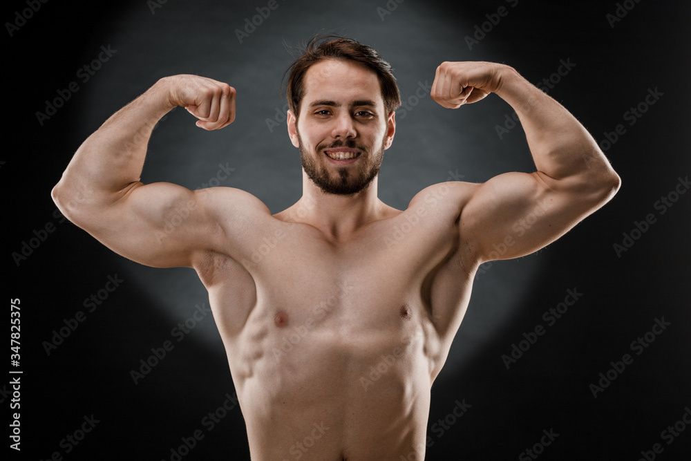 A handsome muscular man without a t-shirt poses for a photographer in a dark photo Studio. The concept of sport A handsome muscular man without a t-shirt poses for a photographer in a dark photo Studio. The concept of sport