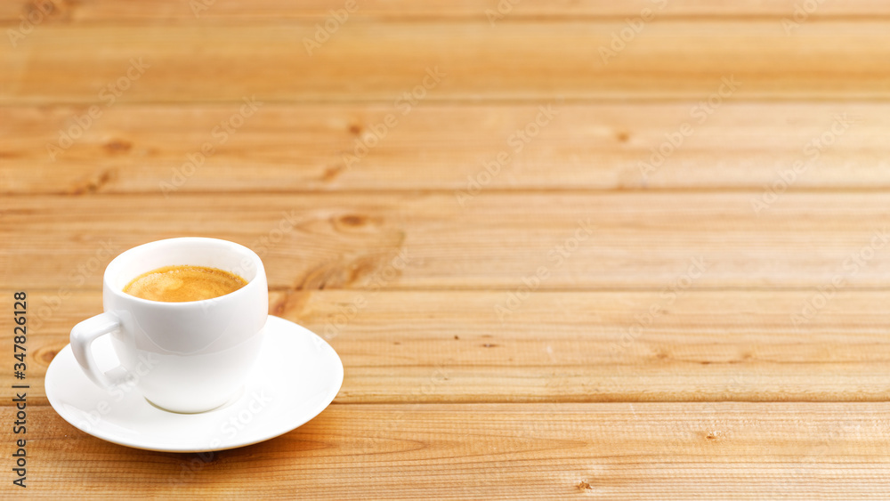 White cup of coffee espresso on wooden background. Shallow focus. Angle view with copyspace. White cup of coffee espresso on wooden background. Shallow focus. Angle view with copyspace.