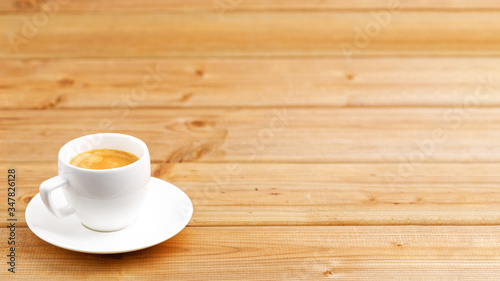White cup of coffee espresso on wooden background. Shallow focus. Angle view with copyspace.