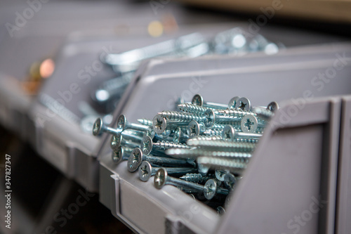 Focus on white silver screws in plastic boxes located on a shelf in a tool and accessories store. Copy space. photo