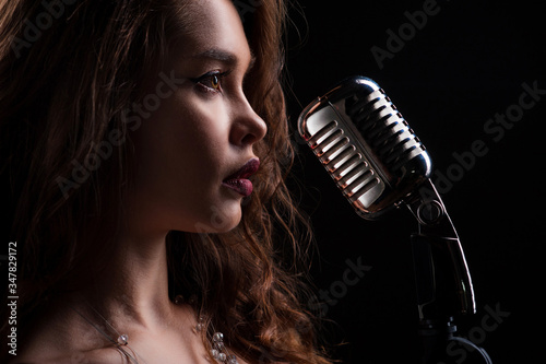 Portrait of a beautiful singer girl. Girl holds microphone in hands