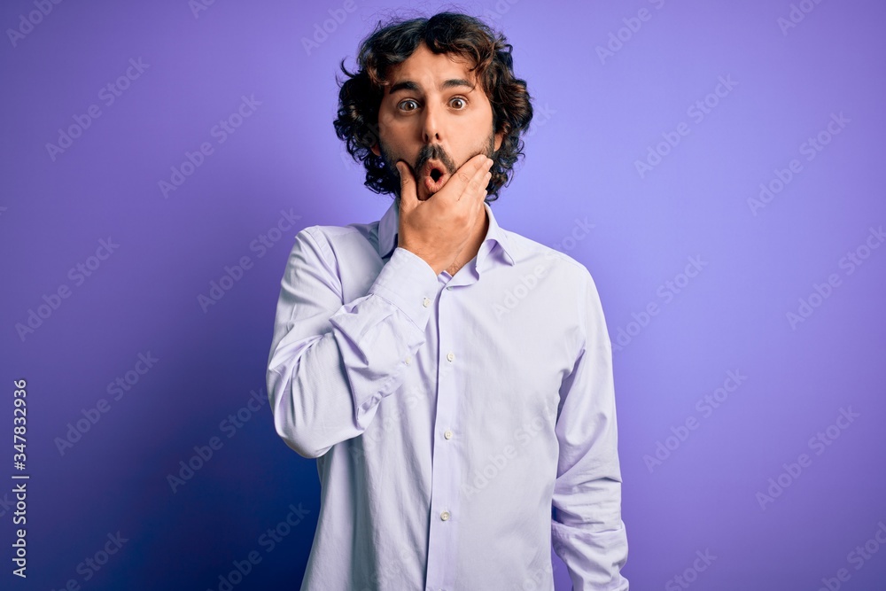 Young handsome business man with beard wearing shirt standing over purple background Looking fascinated with disbelief, surprise and amazed expression with hands on chin Young handsome business man with beard wearing shirt standing over purple background Looking fascinated with disbelief, surprise and amazed expression with hands on chin