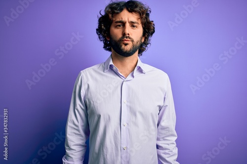 Young handsome business man with beard wearing shirt standing over purple background looking at the camera blowing a kiss on air being lovely and sexy. Love expression. © Krakenimages.com