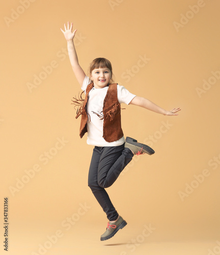 Cute little girl jumping against color background