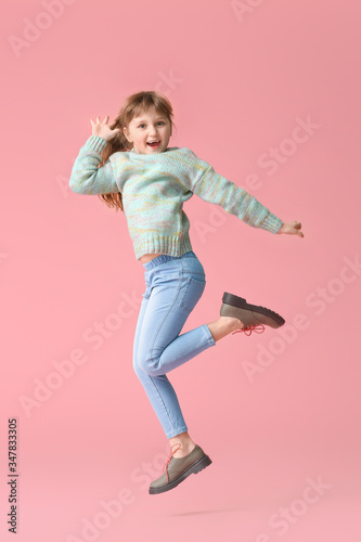 Cute little girl jumping against color background