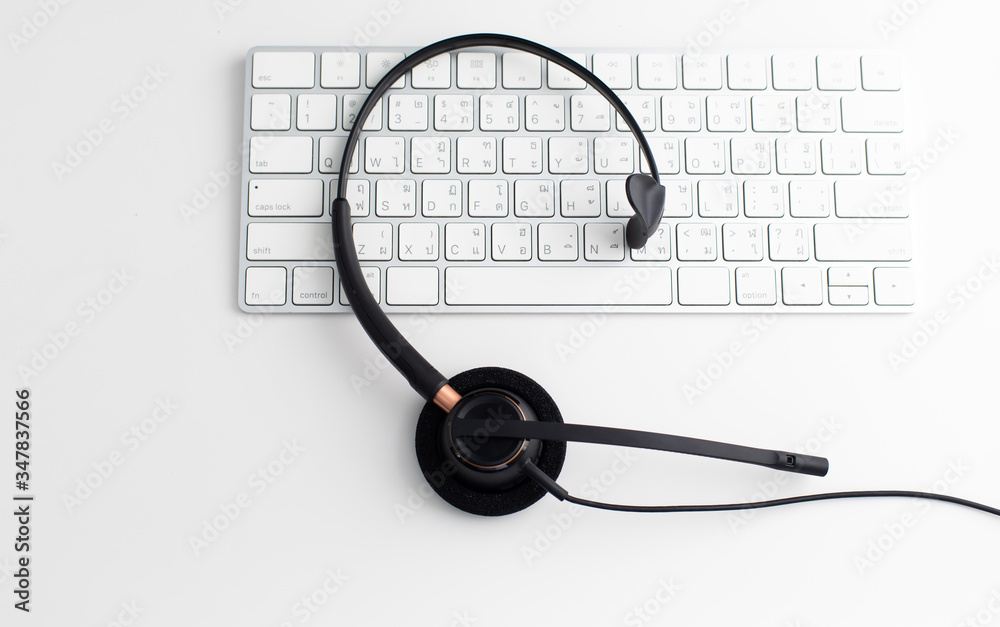 VOIP headset on laptop computer keyboard. Communication support for callcenter and customer service Helpdesk. Isolated on white background. top view flat lay background. Space for text design.. VOIP headset on laptop computer keyboard. Communication support for callcenter and customer service Helpdesk. Isolated on white background. top view flat lay background. Space for text design..
