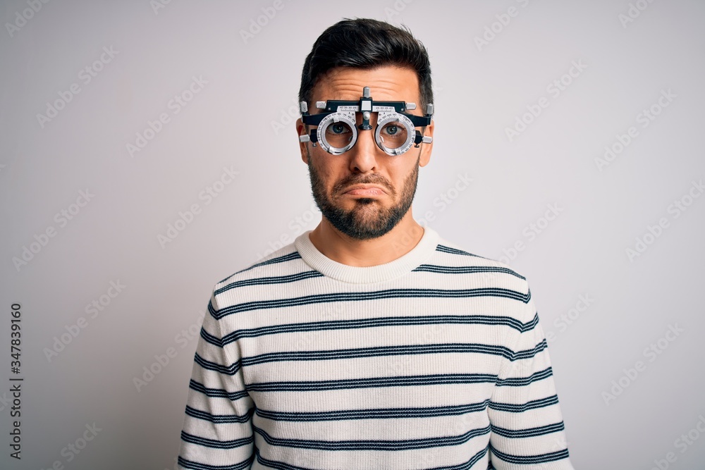Young handsome man with beard wearing optometry glasses over isolated white background depressed and worry for distress, crying angry and afraid. Sad expression. Young handsome man with beard wearing optometry glasses over isolated white background depressed and worry for distress, crying angry and afraid. Sad expression.