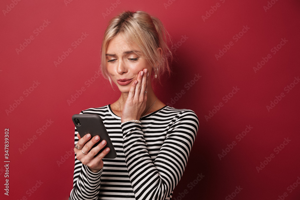Fototapeta premium Image of nice happy woman in striped sweatshirt typing on cellphone