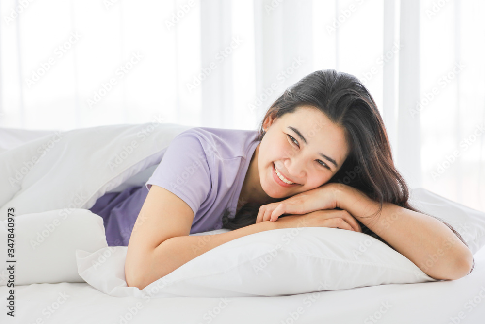 Sleeping girl smiling while lying down on the white bed on her comfy pillow in the morning with copy space Sleeping girl smiling while lying down on the white bed on her comfy pillow in the morning with copy space