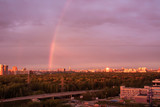 Rainbow over the forest and the city in the distance
