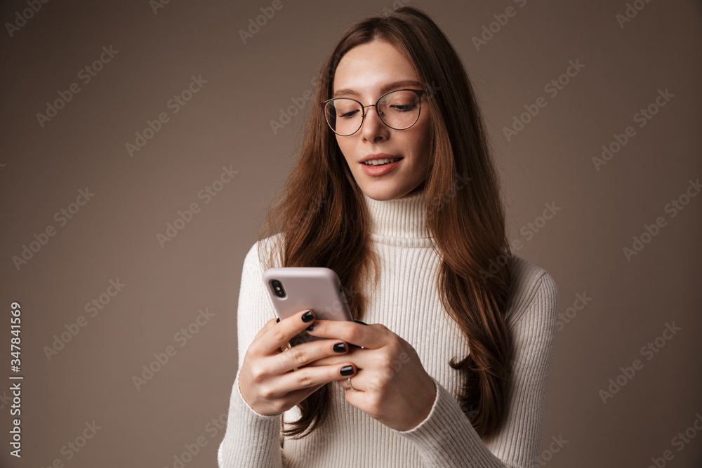 Photo of pleased beautiful woman in eyeglasses typing on cellphone Photo of pleased beautiful woman in eyeglasses typing on cellphone