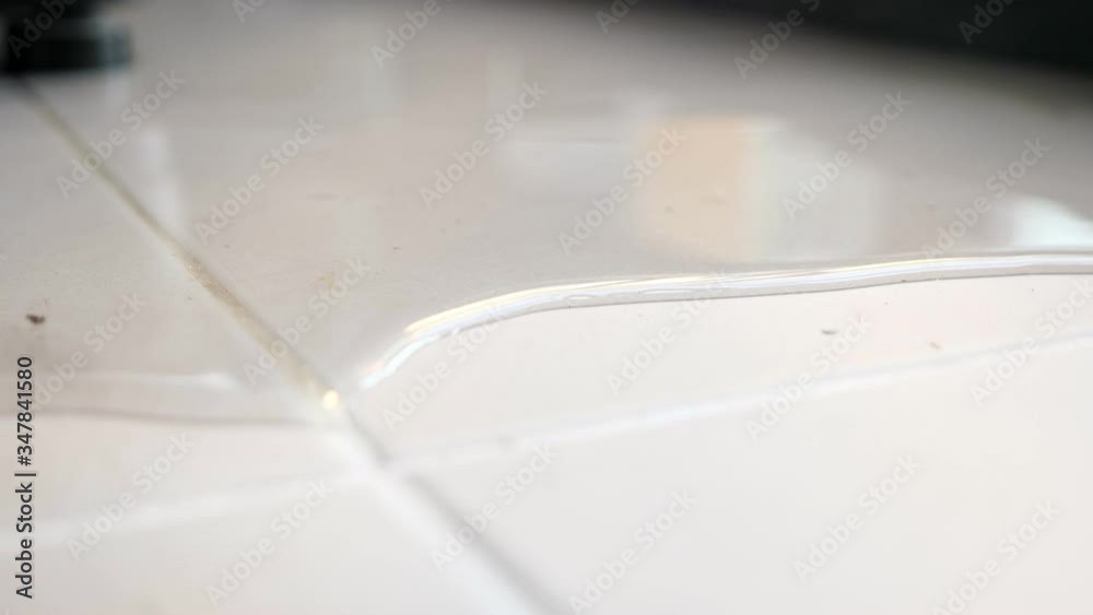 transparent water spreads across floor white tile reflecting blurry window against black furniture after pipe burst closeup