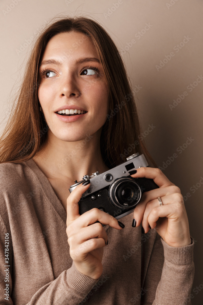 Photo of charming pleased woman looking aside and holding retro camera Photo of charming pleased woman looking aside and holding retro camera