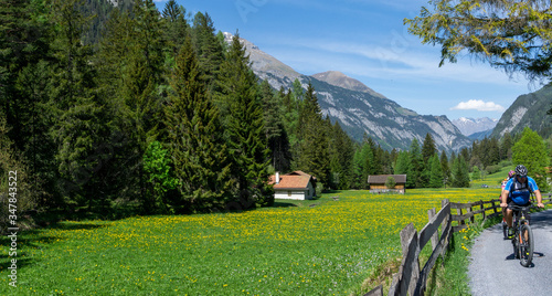 couple enjoys mountain biking in an idyllic Swiss Alps mountain landscape photo