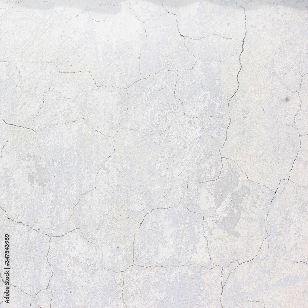the white wall of an old house with beautiful cracks from time. white paint and whitewash on the wall. the background is white with soft blue and yellow. white old wall background the white wall of an old house with beautiful cracks from time. white paint and whitewash on the wall. the background is white with soft blue and yellow. white old wall background