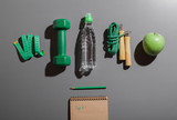 Attributes of a healthy lifestyle in hard light. Fruit, green dumbbell, box, bottle with water, ruler, rope, on a neutral background. Counting calories. The diet plan.  Close-up. Minimalistic concept.