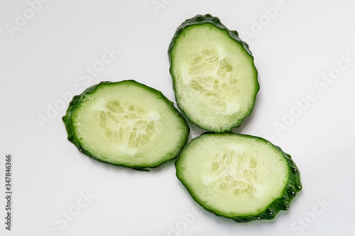 green cucumber cut into pieces on a white background macro shot