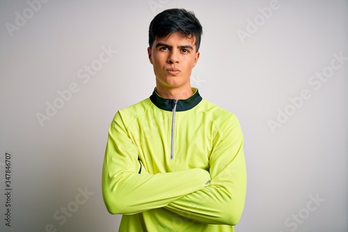 Young handsome sportsman doing sport wearing sportswear over isolated white background skeptic and nervous, disapproving expression on face with crossed arms. Negative person.