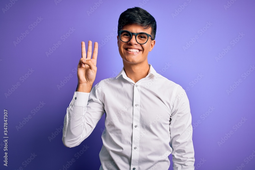 Young handsome business man wearing shirt and glasses over isolated purple background showing and pointing up with fingers number three while smiling confident and happy. Young handsome business man wearing shirt and glasses over isolated purple background showing and pointing up with fingers number three while smiling confident and happy.