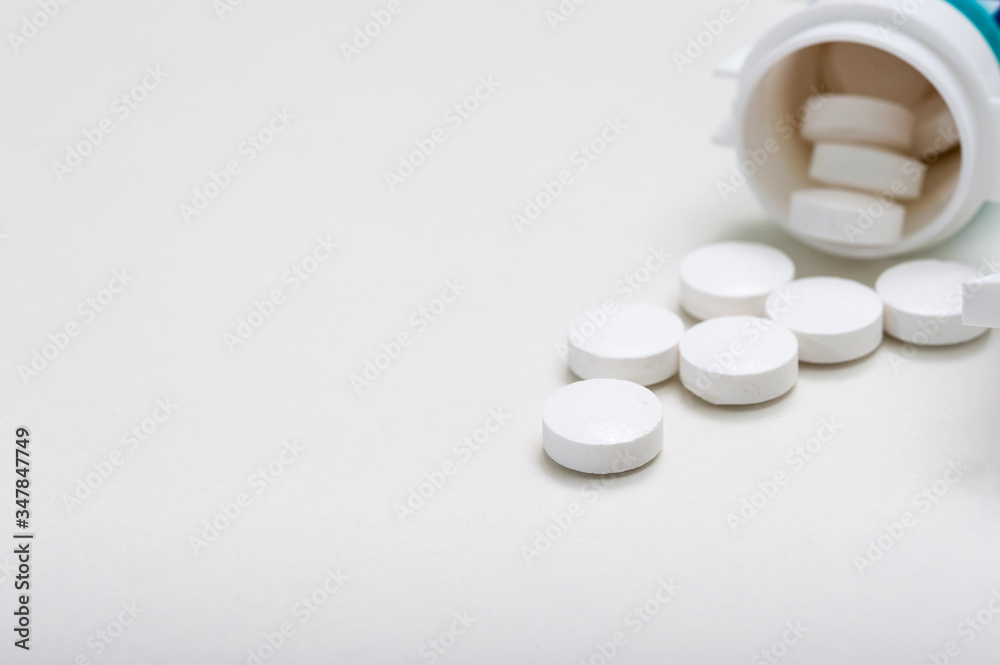 Tablets are poured out of the jar on a white background. Vitamins, medications, front view. Tablets are poured out of the jar on a white background. Vitamins, medications, front view.