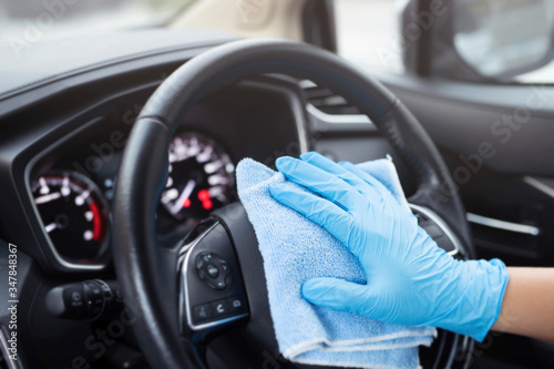 car wash,  worker hand wear glove cleaning console steering wheel with microfiber cloth blue. hygiene prevention  antibacterial of corona virus outbreak. © methaphum