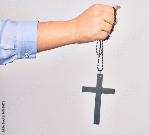 Hand of caucasian young catholic woman holding christian cross over isolated white background