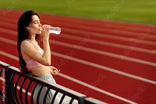 Young beautiful girl drinking water at the stadium