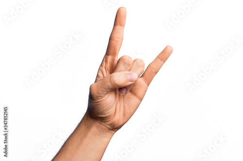 Hand of caucasian young man showing fingers over isolated white background gesturing rock and roll symbol, showing obscene horns gesture photo