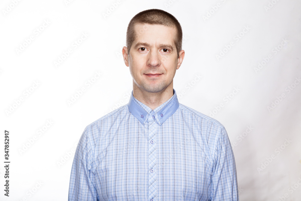portrait of a confident calm, strict man, in a blue classic shirt; look into the camera. Isolated portrait of a confident calm, strict man, in a blue classic shirt; look into the camera. Isolated