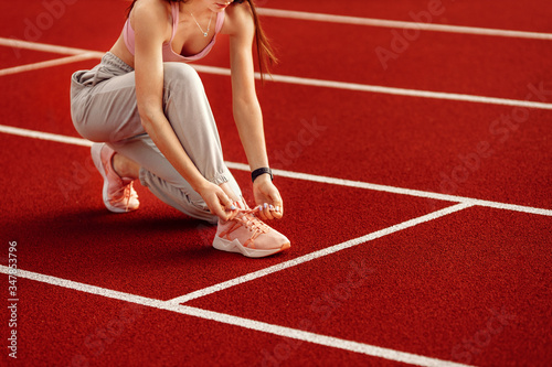 Athlete woman tying shoelaces before running at the stadium